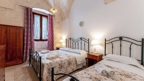 Un dormitorio con dos camas, un armario de madera y una ventana con cortinas.