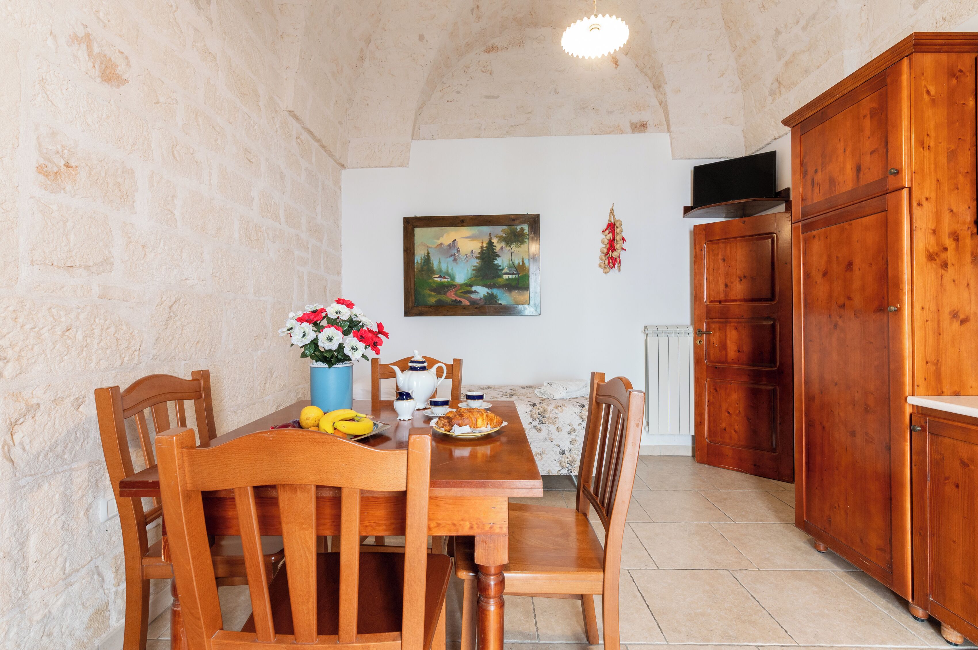 Uma sala de jantar com mesa de madeira, cadeiras e um quadro na parede.
