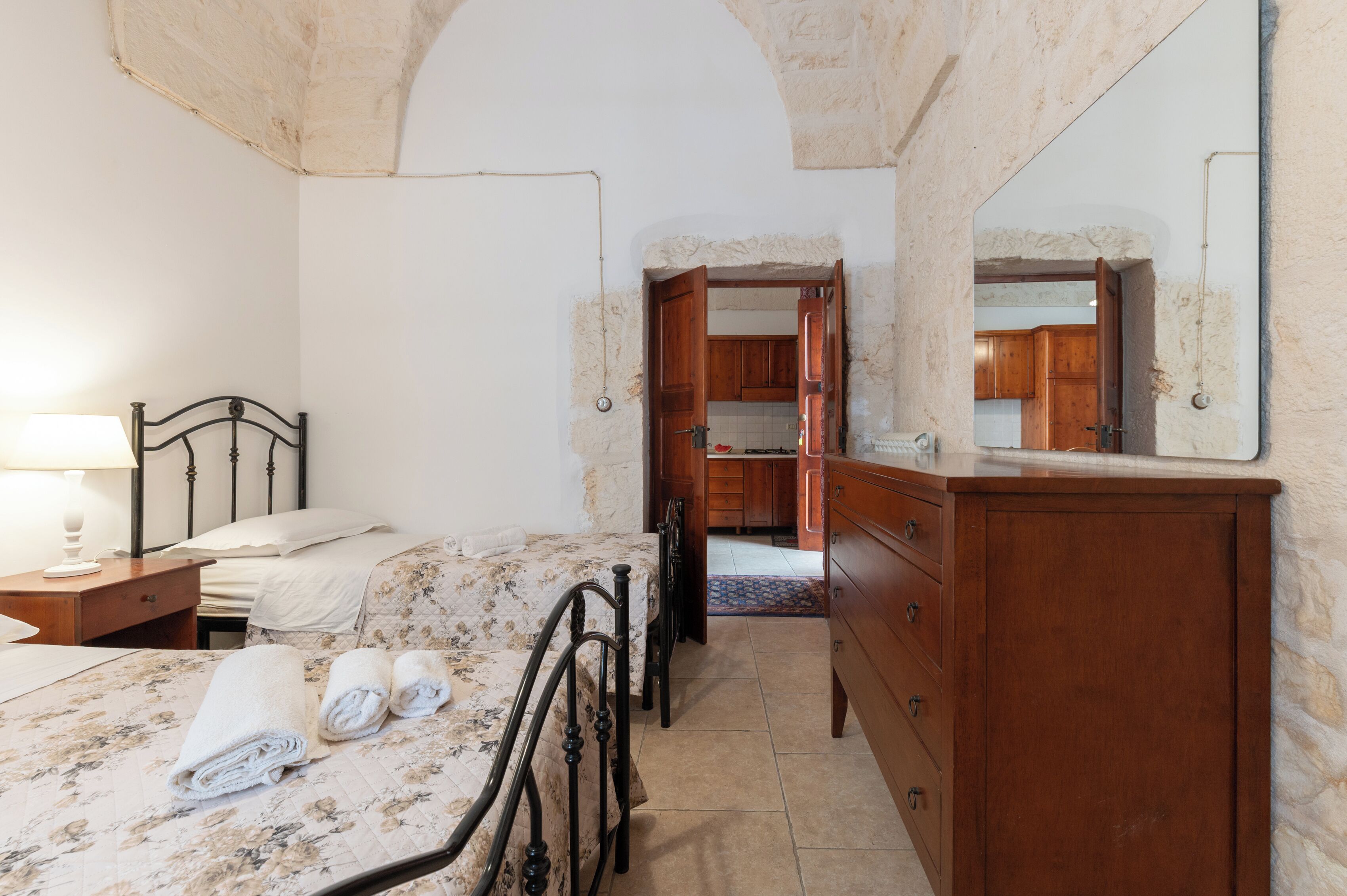 Un dormitorio con cama, cómoda de madera y baño visible a través de una puerta abierta.