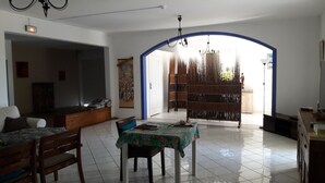 Un amplio salón con mesa de comedor, sillas, sofá y un biombo decorativo.