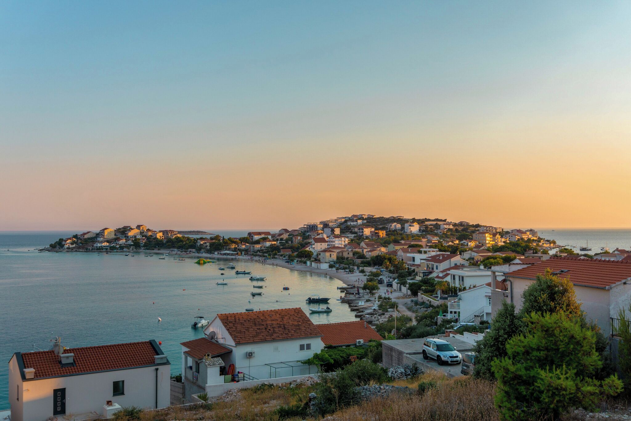A coastal town with buildings along the waterfront, boats in the water, and a clear view of the sea.