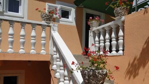 Un escalier avec des balustrades blanches et des rampes en pierre, menant à un balcon agrémenté de plantes en pot.