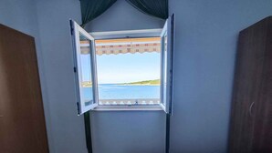 Une chambre à coucher avec un lit, une fenêtre donnant sur la mer et une porte en bois.