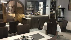 A modern dining area with a bar, dark wood furniture, and pendant lighting. - Hotel Gurmán (Horšovský Týn)