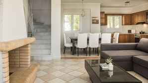 A modern living room with a fireplace, a dining area, and a kitchen.