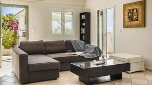 A modern living room with a sectional sofa, a glass coffee table, and a bookshelf.