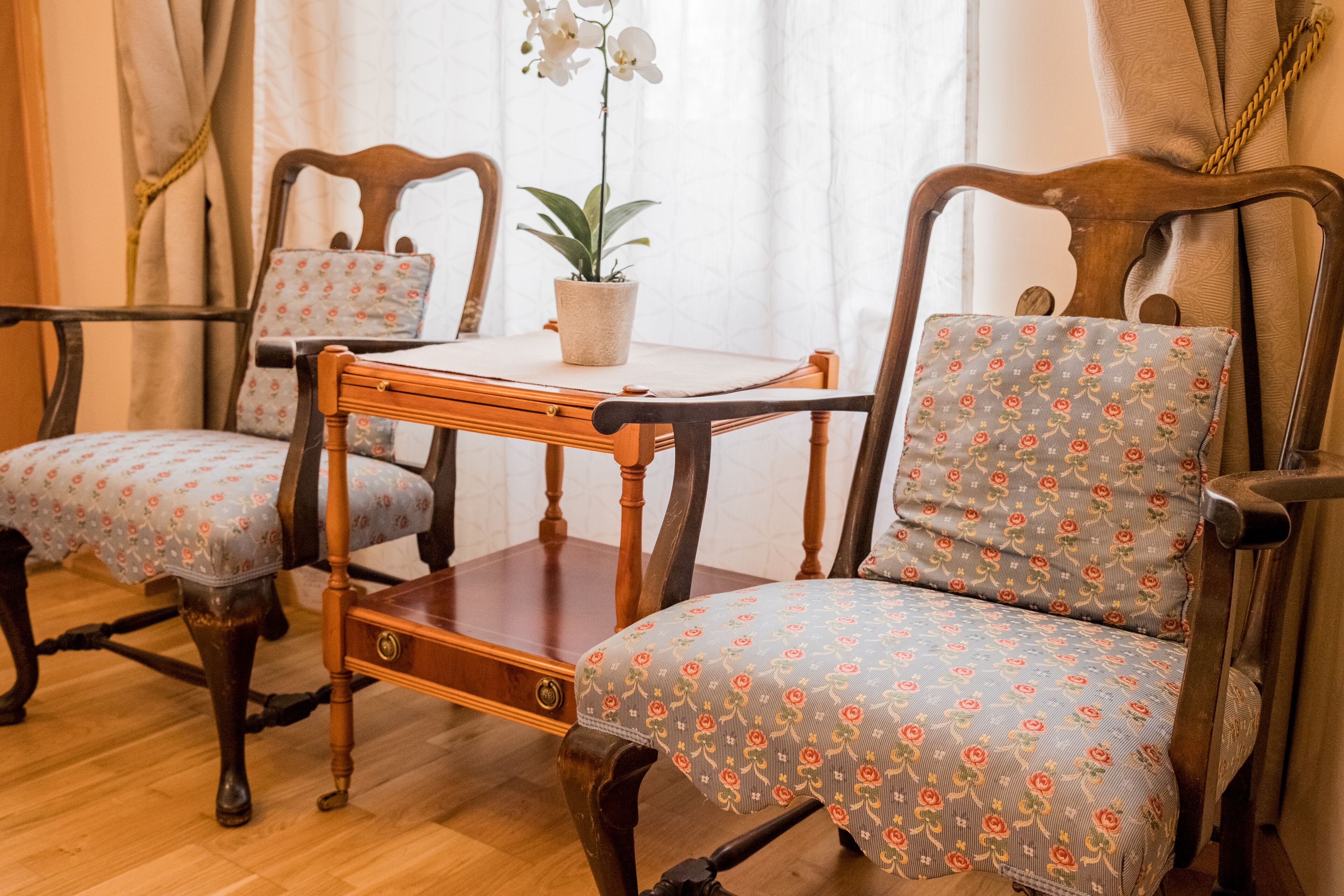 Una habitación con una mesa de madera y dos sillas con tapicería floral.