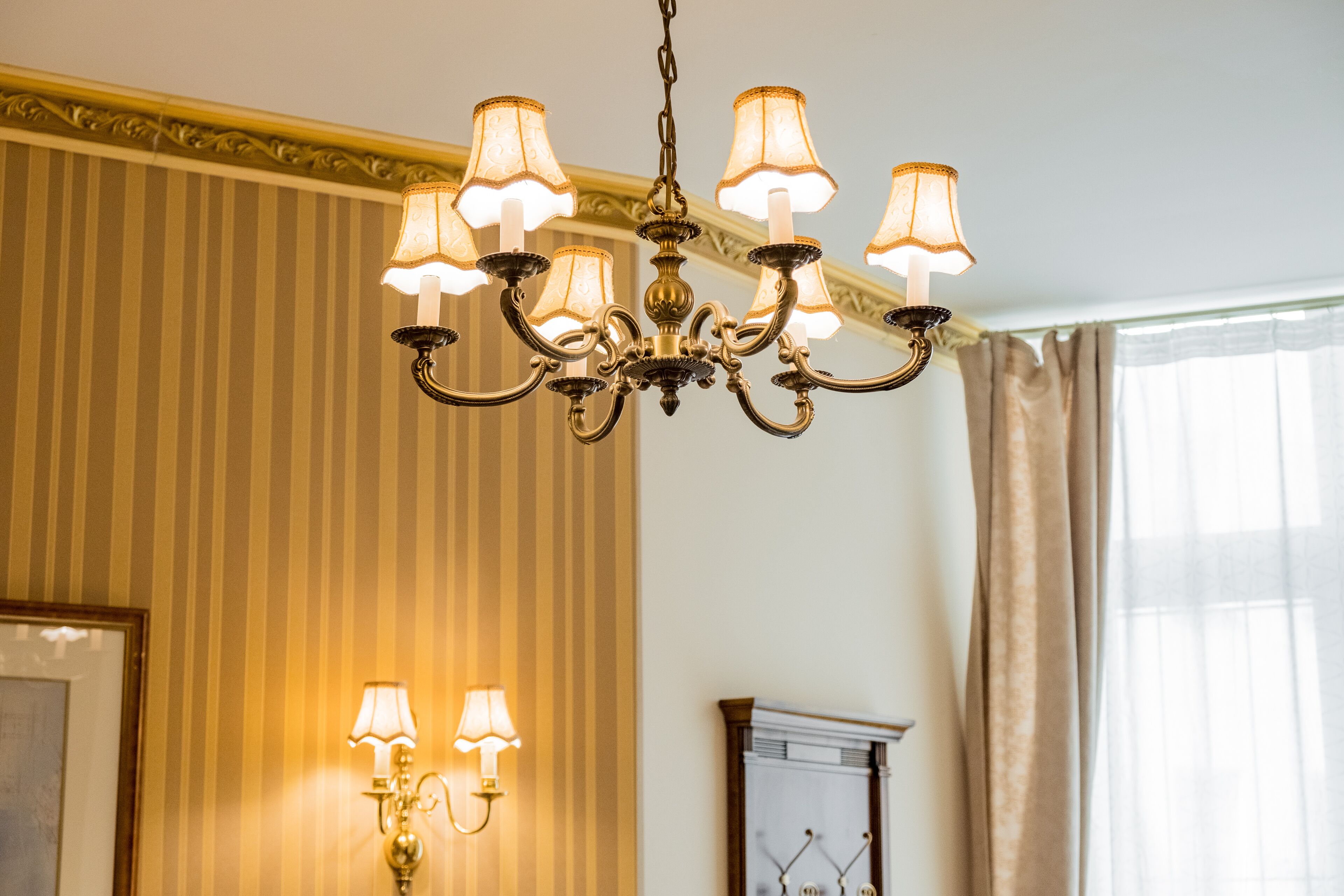 Un candelabro con varias lámparas, una lámpara de pared y un cuadro enmarcado.
