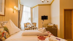 Una habitación de hotel con cama, televisión, zona de comedor y sofá.