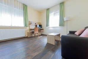 A room with a desk, chair, TV, and a sofa. - Hotel Restaurante Lorca (Weinsberg)