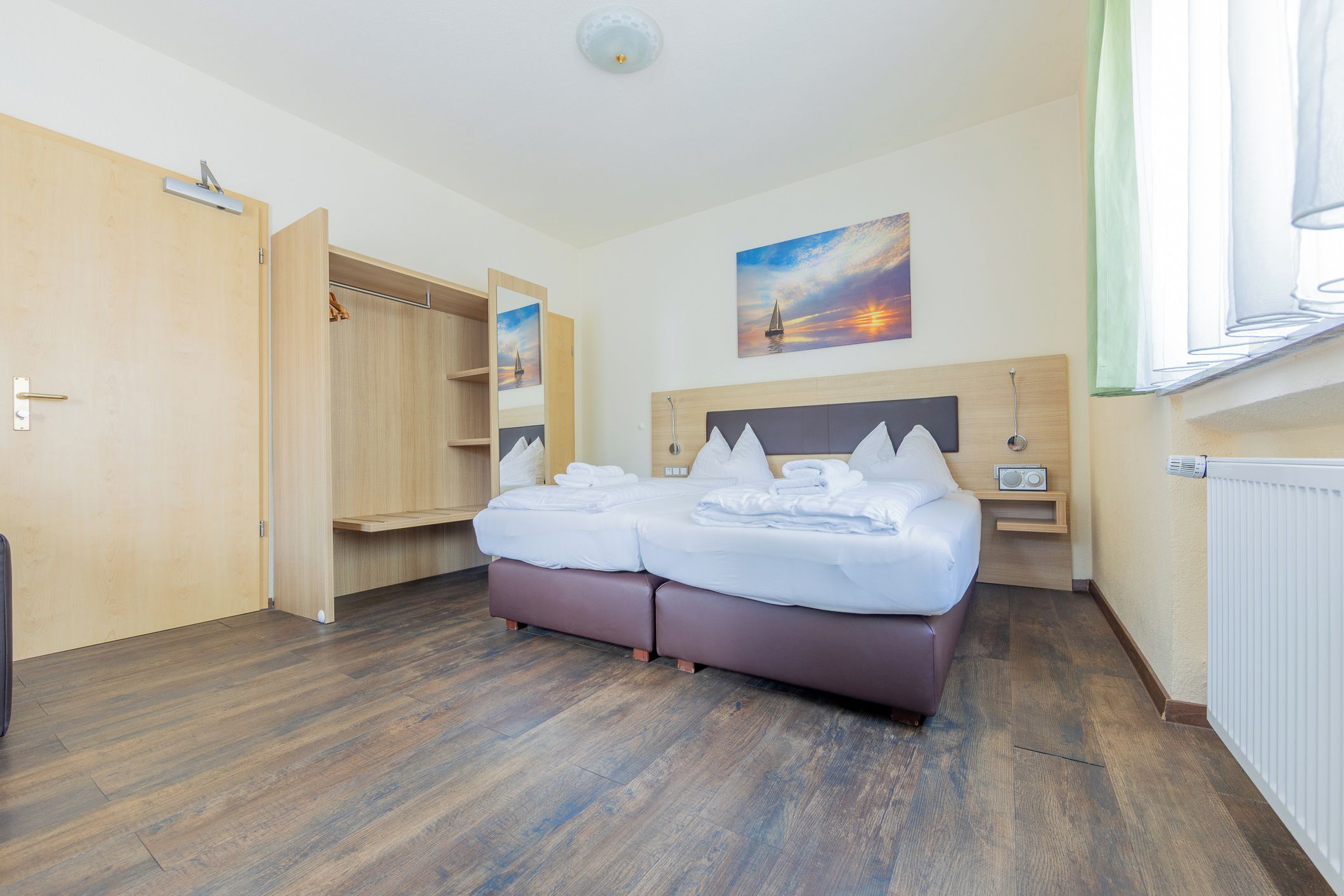 Une chambre d’hôtel avec un lit, une armoire, un tableau et une fenêtre.