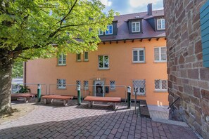 A building with multiple windows, a paved courtyard, and benches. - Hotel Restaurante Lorca (Weinsberg)
