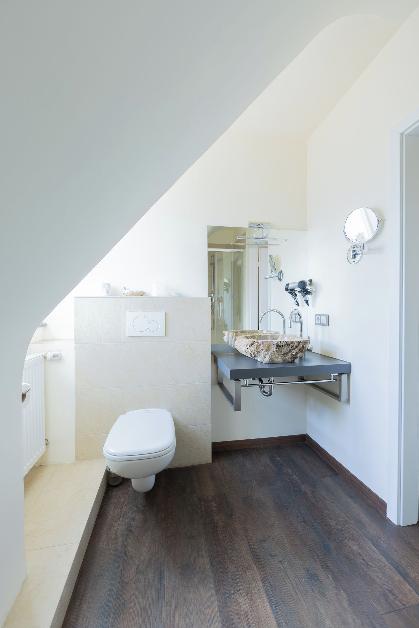 A modern bathroom with a toilet, a sink with a stone basin, and a shower.