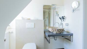 A modern bathroom with a toilet, a sink with a stone basin, and a shower.
