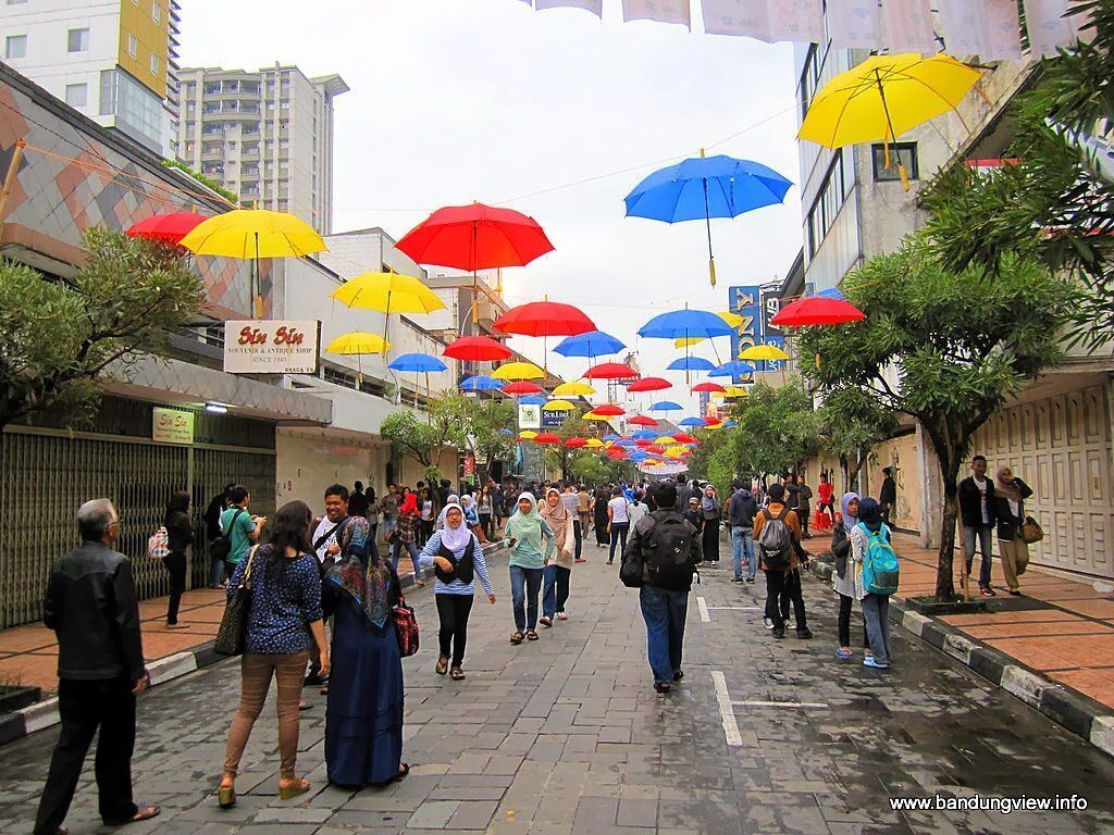 A street lined with colorful umbrellas, a sign for 'Siti Siti', and people walking.
