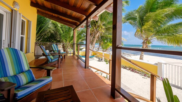 Un espacio de estar al aire libre cubierto con vistas a la playa y palmeras.