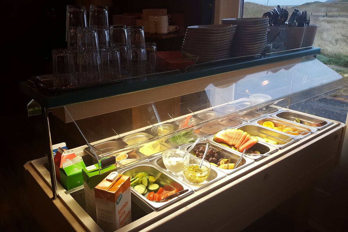 Un bufé con diversas opciones de comida y un dispensador de zumo.