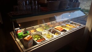 Een buffet met diverse eetopties, zoals fruit, groenten en drankjes.