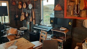 Een muziekstudio met diverse instrumenten, een drumstel, een keyboard en een mengpaneel.