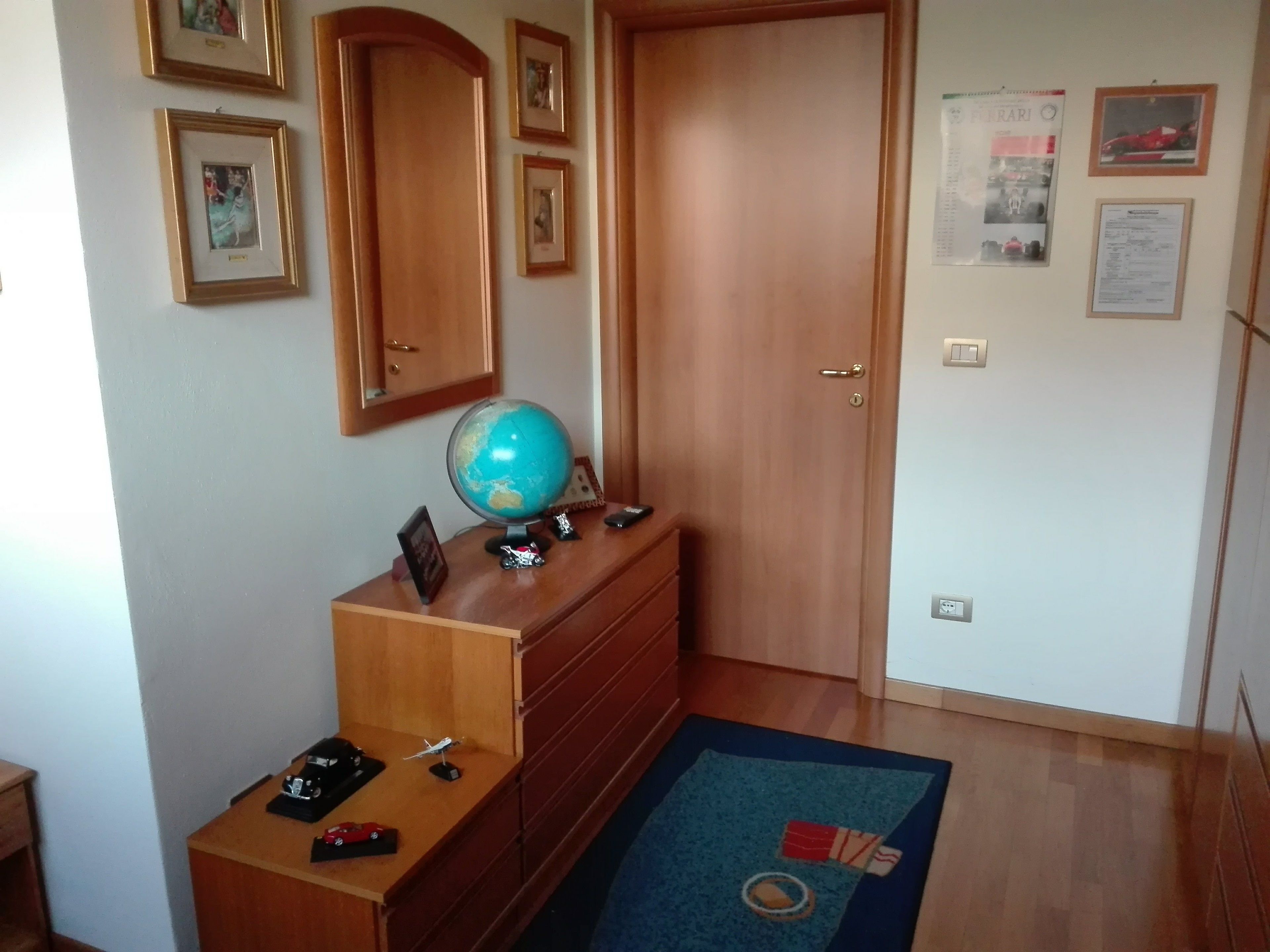 A room with a wooden dresser, a globe, and a desk with a red toy car.