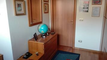 A room with a wooden dresser, a globe, and a desk with a red toy car.