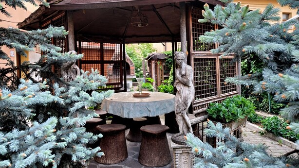 A gazebo with a round table and stools, surrounded by coniferous trees and a birdcage. - B&B Il Cantastorie Casa Molinari-Boldrini (Castelfranco Emilia)