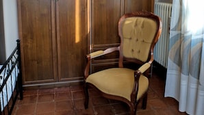 A room with a large wooden wardrobe, a classic armchair, a floral rug, and a radiator. - B&B Il Cantastorie Casa Molinari-Boldrini (Castelfranco Emilia)