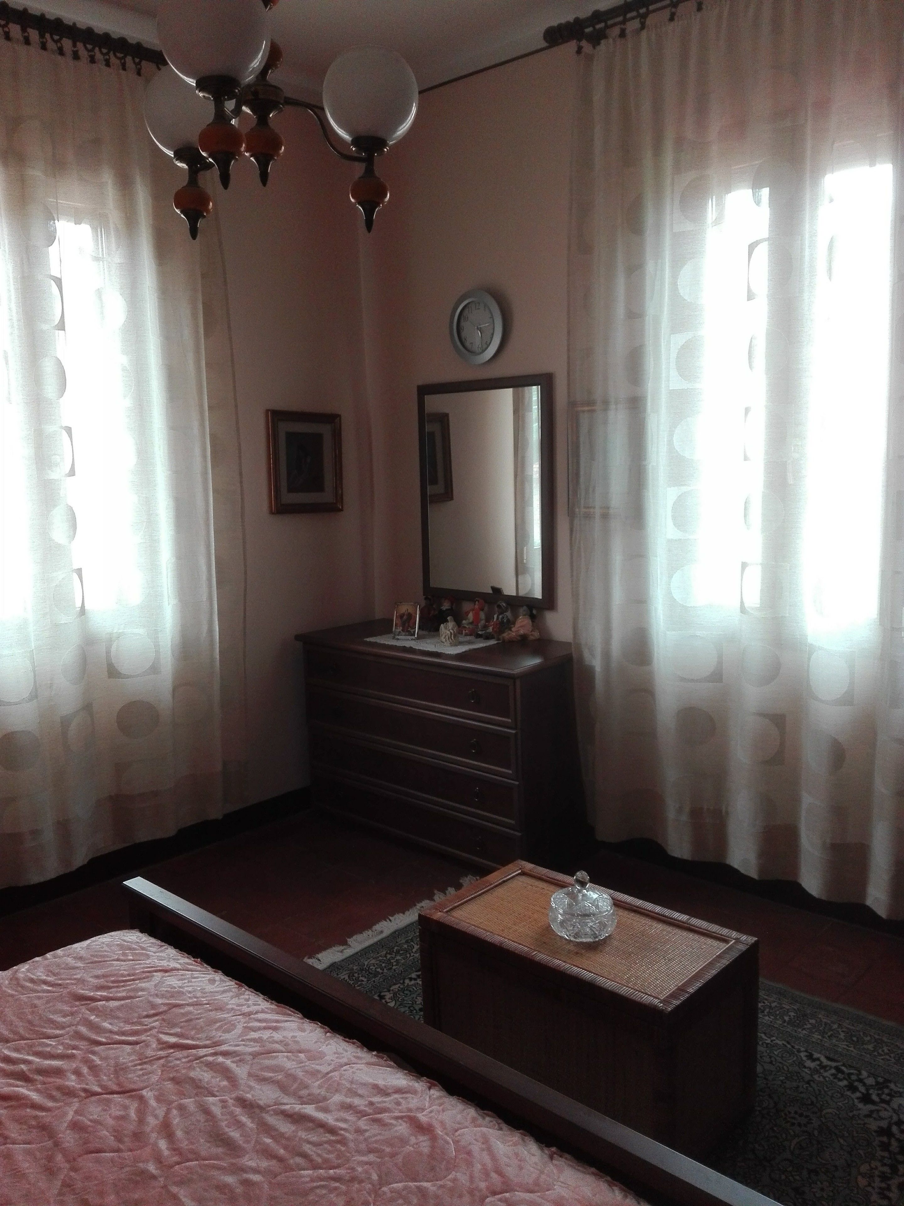 Un dormitorio con cama, cómoda, espejo, reloj y candelabro.