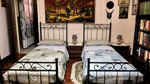 A bedroom with two beds, a bookshelf, a painting, and a clock on the wall. - B&B Il Cantastorie Casa Molinari-Boldrini (Castelfranco Emilia)