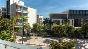 A modern building with multiple floors, balconies, and a paved courtyard with trees and a fence. - Nemesis Hotel (Sarandë)