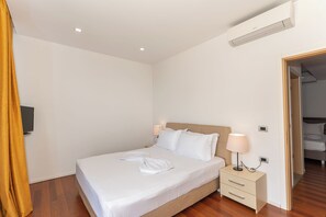 A hotel room with a bed, bedside lamps, a flat-screen TV, and a wooden floor. - Nemesis Hotel (Sarandë)