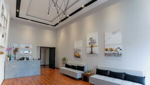 A spacious lobby with a reception desk, two sofas, and artwork on the walls. - Nemesis Hotel (Sarandë)