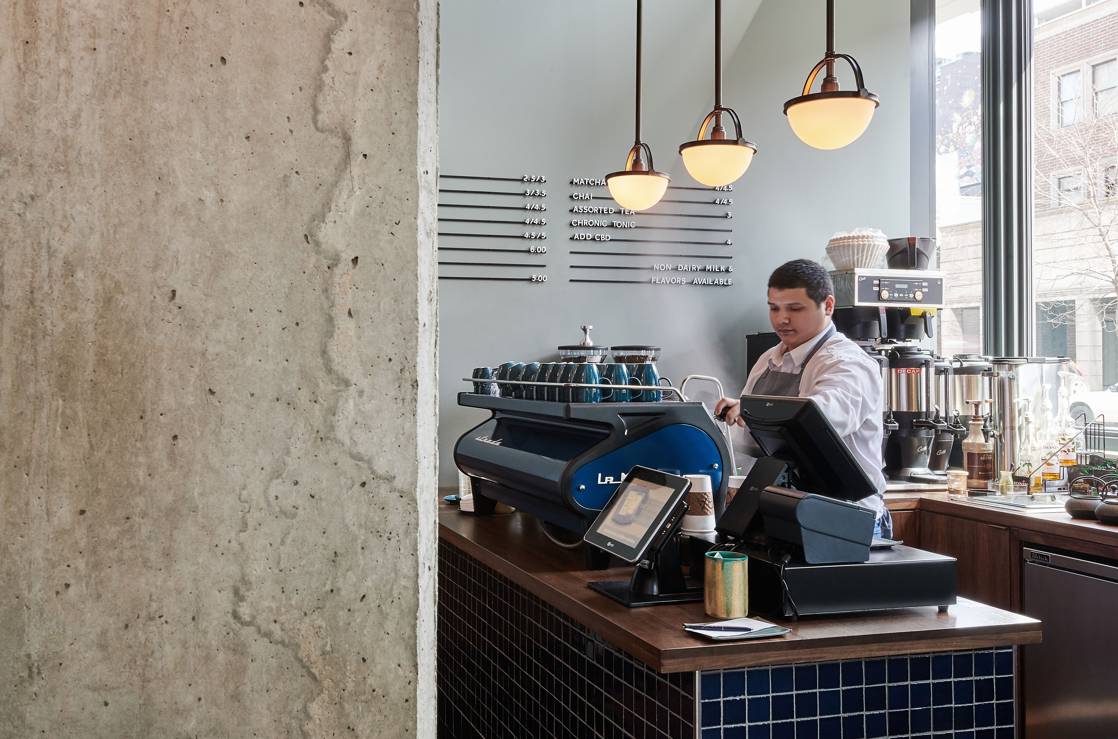 Ein Café-Interieur mit einer Speisekarte an der Wand, einer Kaffeemaschine und einer Theke.