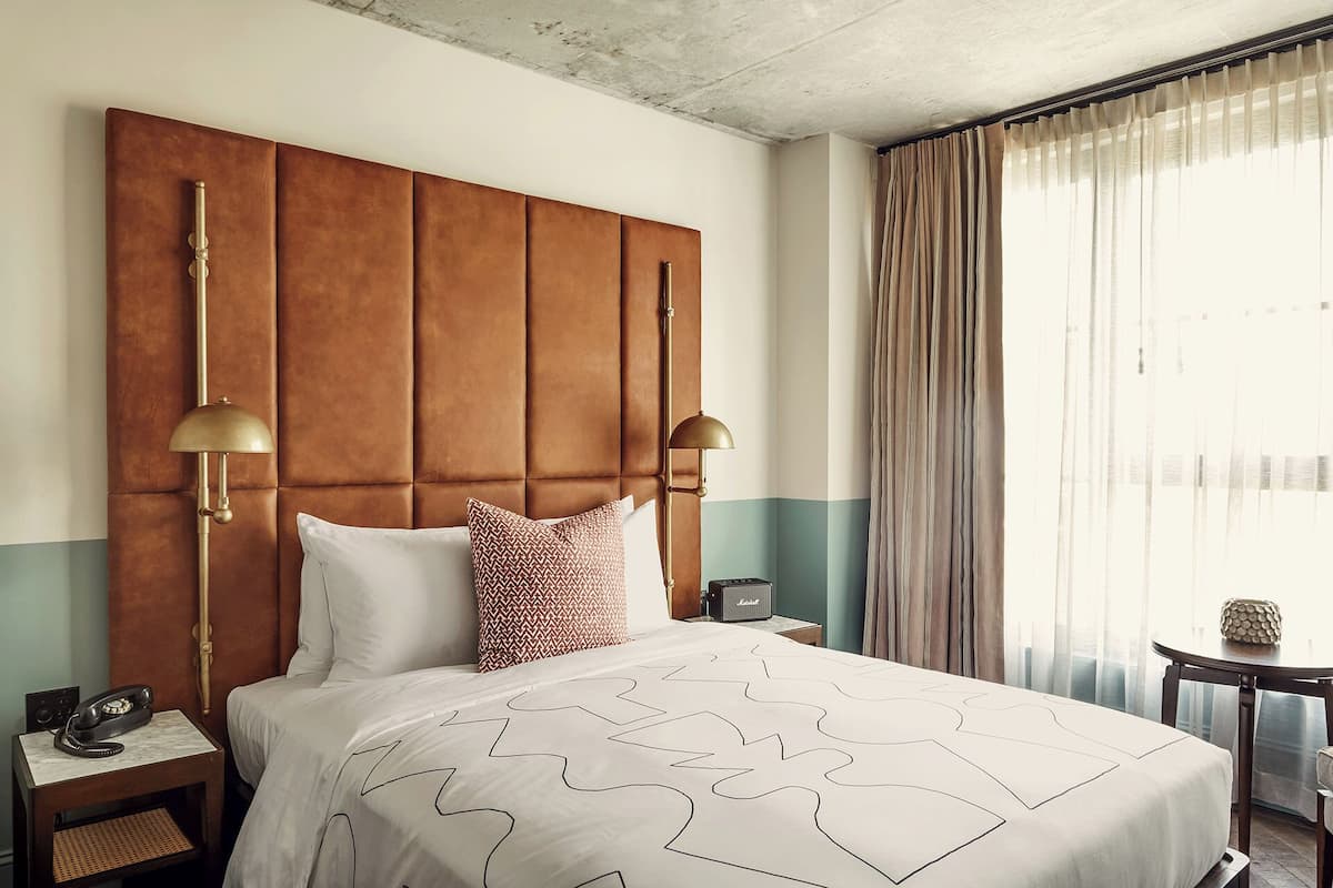 A hotel room with a large bed, two bedside lamps, a telephone, and a small table with a lamp.