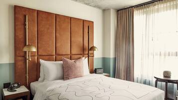 A hotel room with a large bed, two bedside lamps, a telephone, and a small table with a lamp.