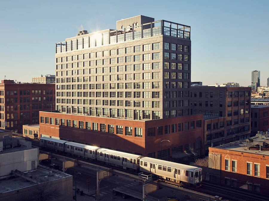 A multi-story building with a modern architectural design, featuring a prominent glass facade and a rooftop terrace.