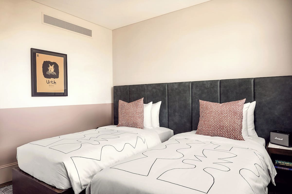 A hotel room with two beds, a framed picture on the wall, and a nightstand with a radio.