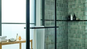 A bathroom with a glass shower enclosure, a wooden bench, and a towel rack.