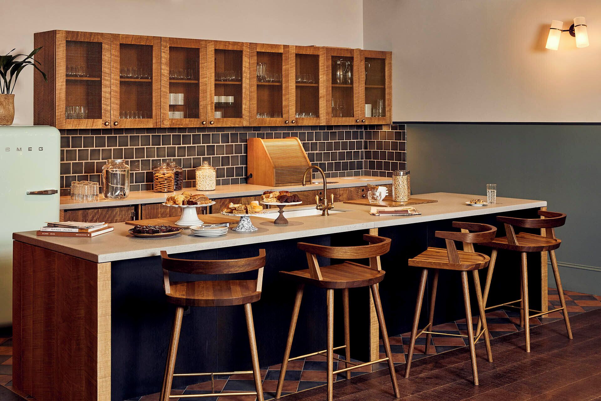 A modern kitchen with a central island, bar stools, wooden cabinets, and a tiled backsplash.