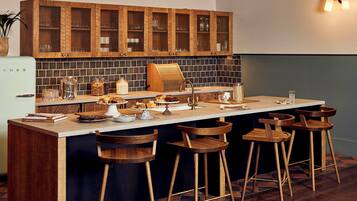 Cozinha moderna com ilha central, banquetas, armários de madeira e painel de azulejos.
