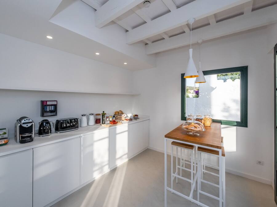 A modern kitchen with white cabinetry, a wooden bar counter, and a window providing natural light.