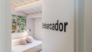 Une chambre d’hôtel moderne, équipée d’un lit, d’une œuvre d’art accrochée au mur et d’une pancarte indiquant « Embarcador ».