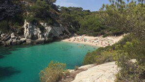 Une plage côtière bordée d’une eau turquoise et limpide, de falaises rocheuses et d’une végétation luxuriante.