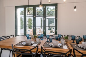 A dining area with a wooden table set for six, blue glassware, and black chairs. - Hotel m - 27 (Mercadal)