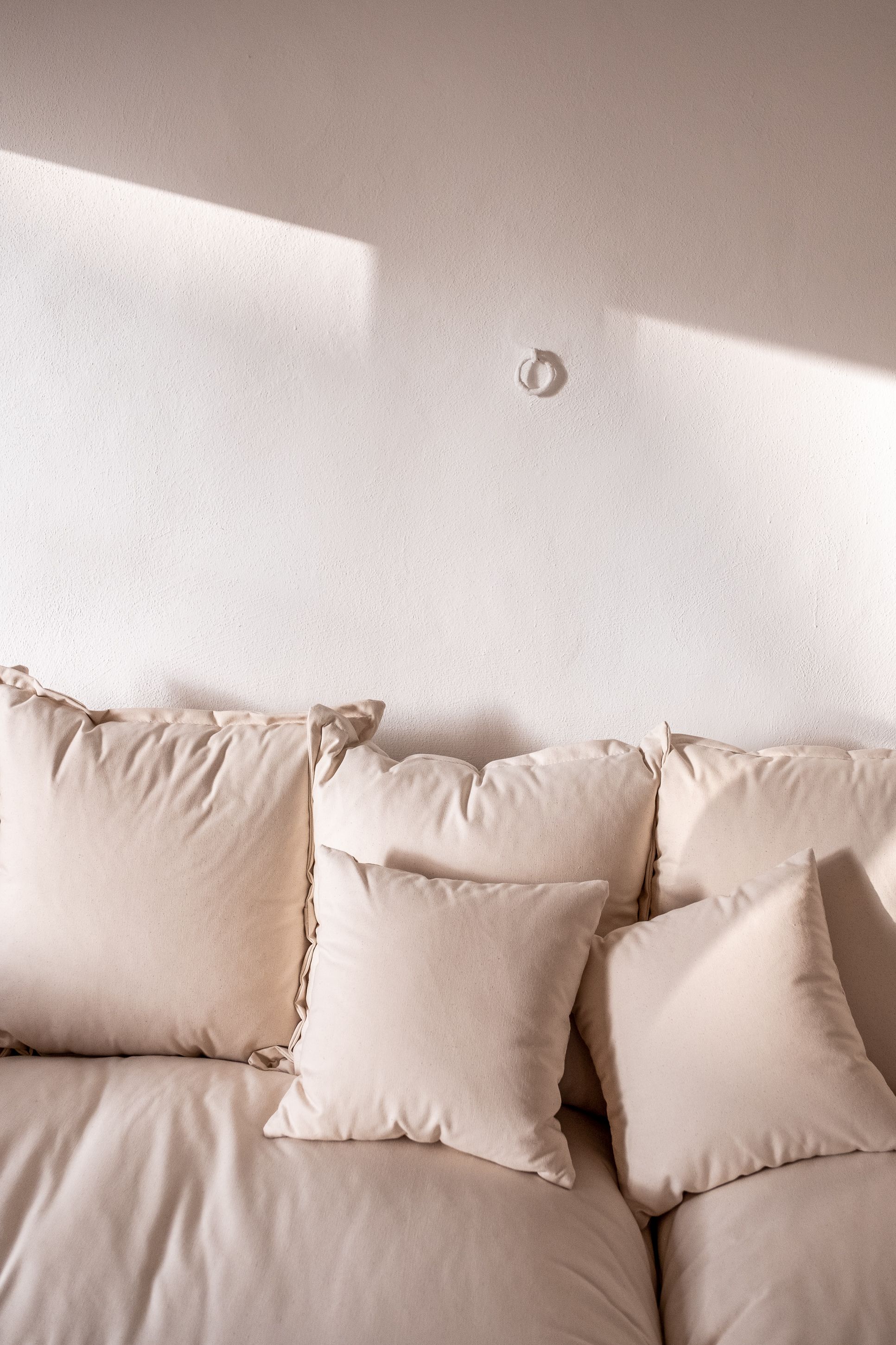 A bed with multiple pillows and a plain wall.