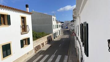 A narrow street lined with white buildings, some with balconies and shutters.