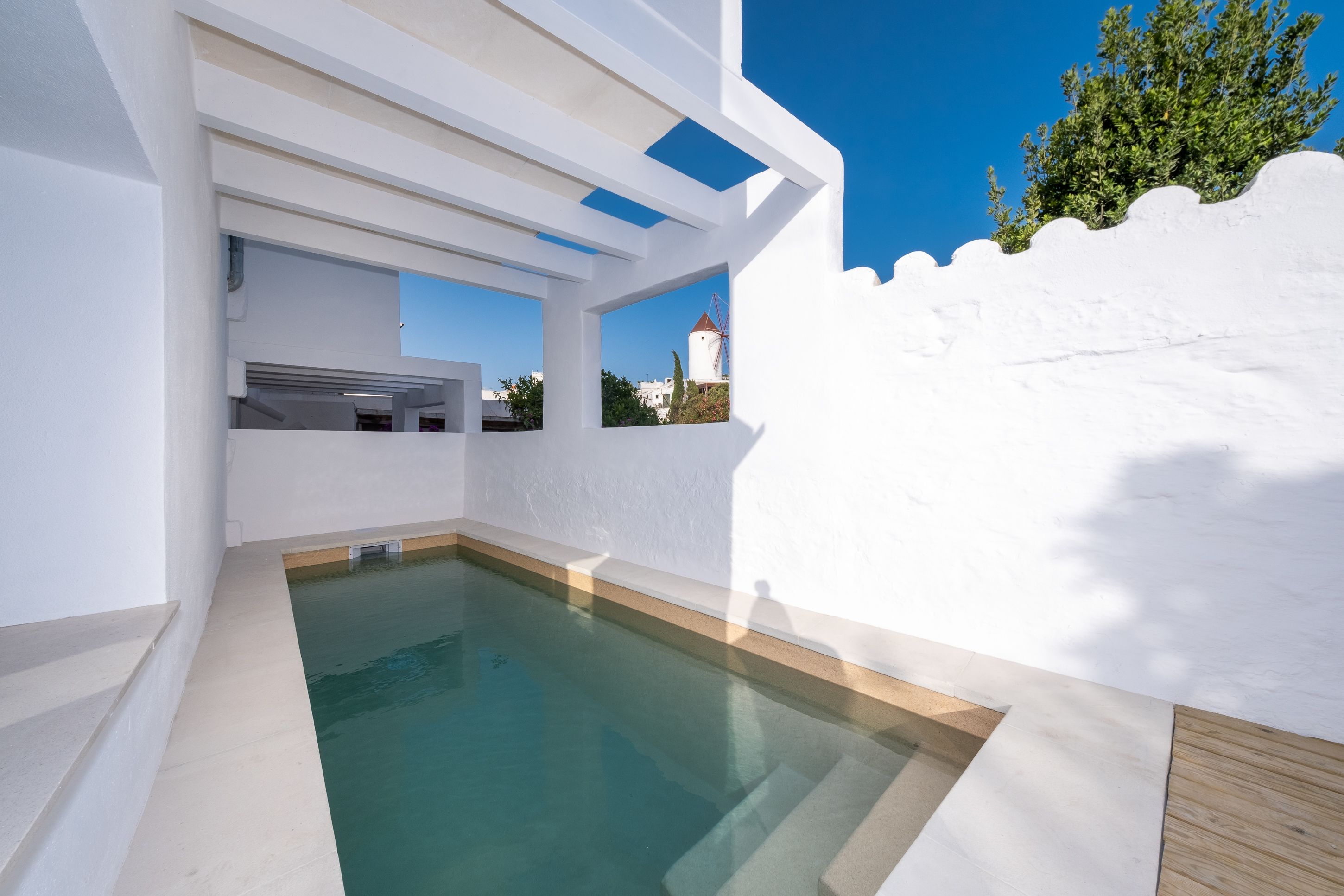A modern pool area with a clear view of the sky and a windmill in the background.