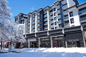 A multi-story building with balconies and storefronts, including a sports store.