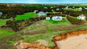 Une vue aérienne d’une zone côtière avec des maisons, une plage et une forêt.