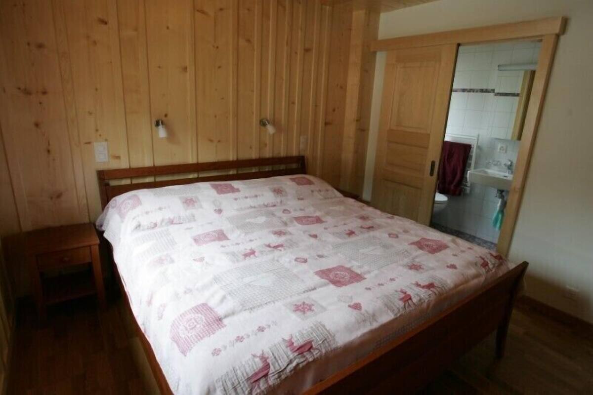 Un dormitorio con una cama de madera, una mesita de noche y un armario de madera.